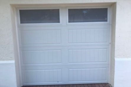 Detailed view of a single white garage door with vertical panel design and upper windows, installed by Garage Door Repair Treasure Island in Clearwater.
