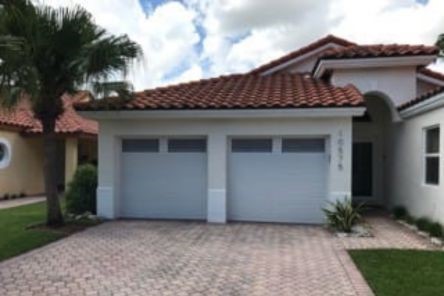 Front view of a Clearwater home with two newly installed white garage doors and a red tile roof, showcasing upgraded curb appeal.