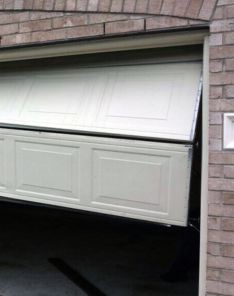 Garage door panel collapsed and tilted at an angle, illustrating a major off-track garage door problem in a Saint Pete Beach home.