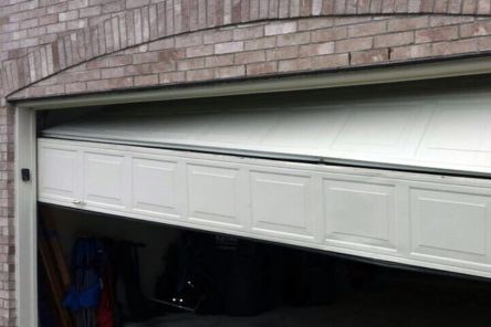Garage door panel collapsed and tilted at an angle, illustrating a major off-track garage door problem in a Saint Pete Beach home.