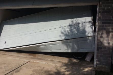 Garage door panel collapsed and tilted at an angle, illustrating a major off-track garage door problem in a Saint Pete Beach home.