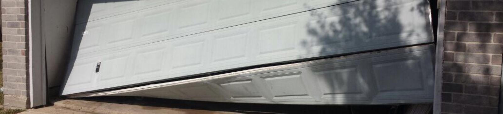 Garage door panel collapsed and tilted at an angle, illustrating a major off-track garage door problem in a Saint Pete Beach home.