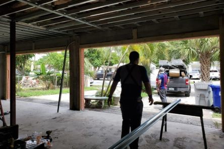 Technician working inside the garage, preparing the opening and hardware for the new double garage door installation in Treasure Island.