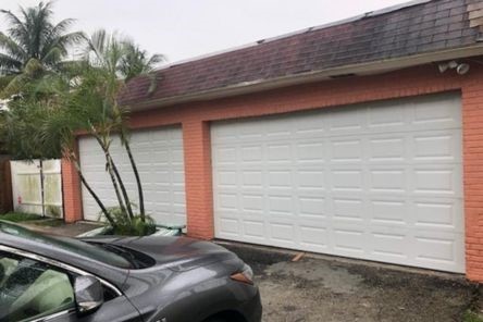 Completed installation of a new white double garage door on a brick home in Treasure Island, enhancing curb appeal and security.