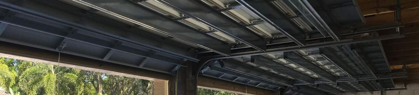 Interior view of new steel tracks and ceiling supports being installed for a double garage door in a Treasure Island home.