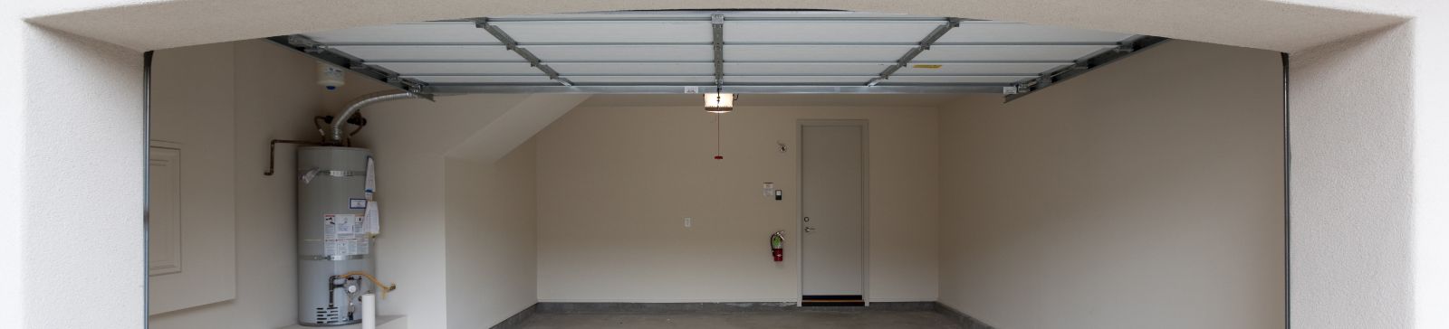 Interior view of a modern, empty garage with an open overhead garage door and visible automatic opener, illustrating innovative garage door technologies